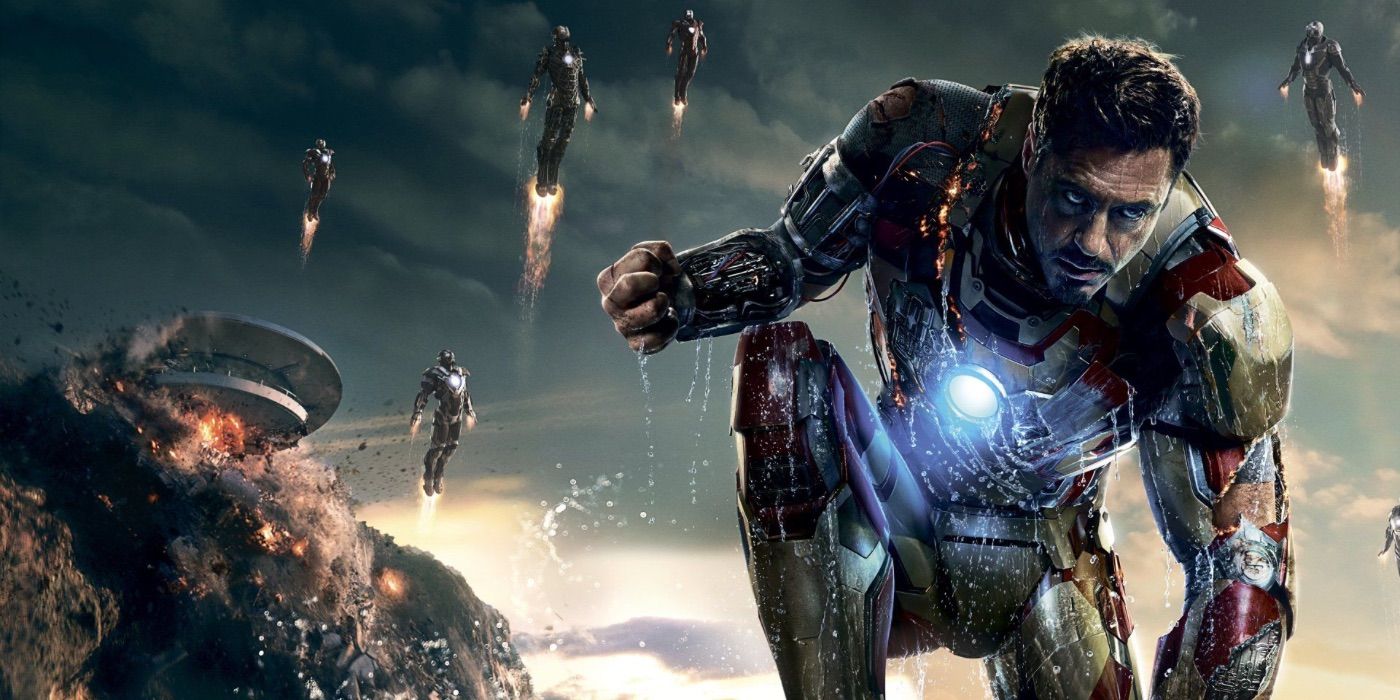 Robert Downey Jr as Iron Man kneeling as multiple Iron Man suits fly behind him in Iron Man 3.
