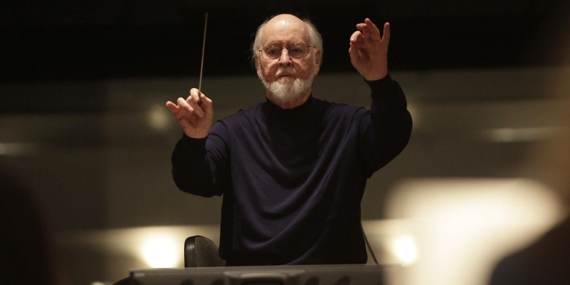 John Williams conducting in front of a blurry background