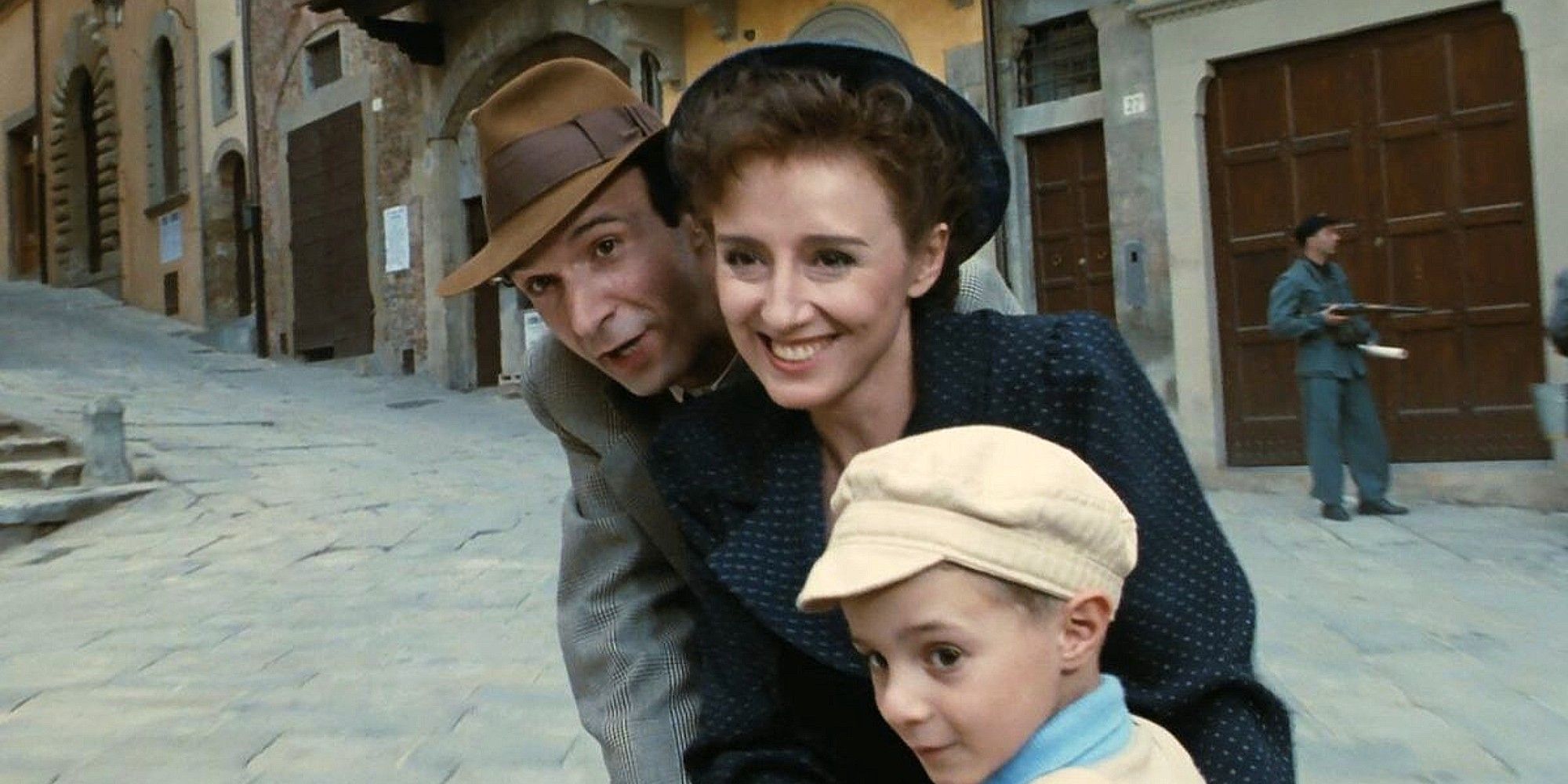 Guido, Dora, and Giosué laughing while riding a bike in 'Life is Beautiful'