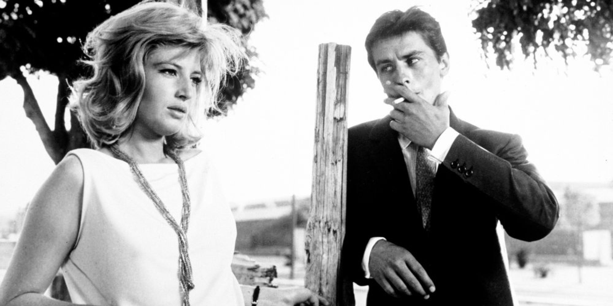 Alain Delon and a woman stand outside as he smokes a cigarette in L’Eclisse - 1962