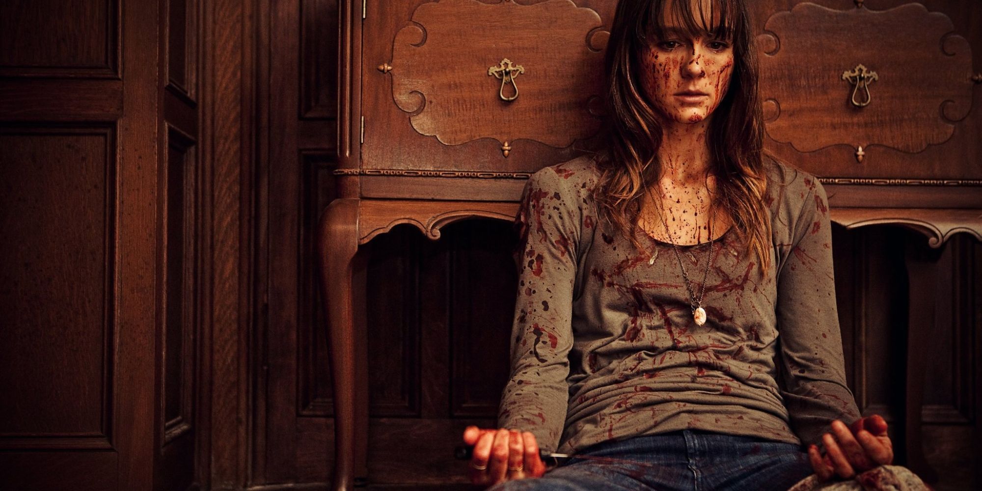 Sharni Vinson dans le rôle d'Erin couverte de sang assise sur le sol dans You're Next.
