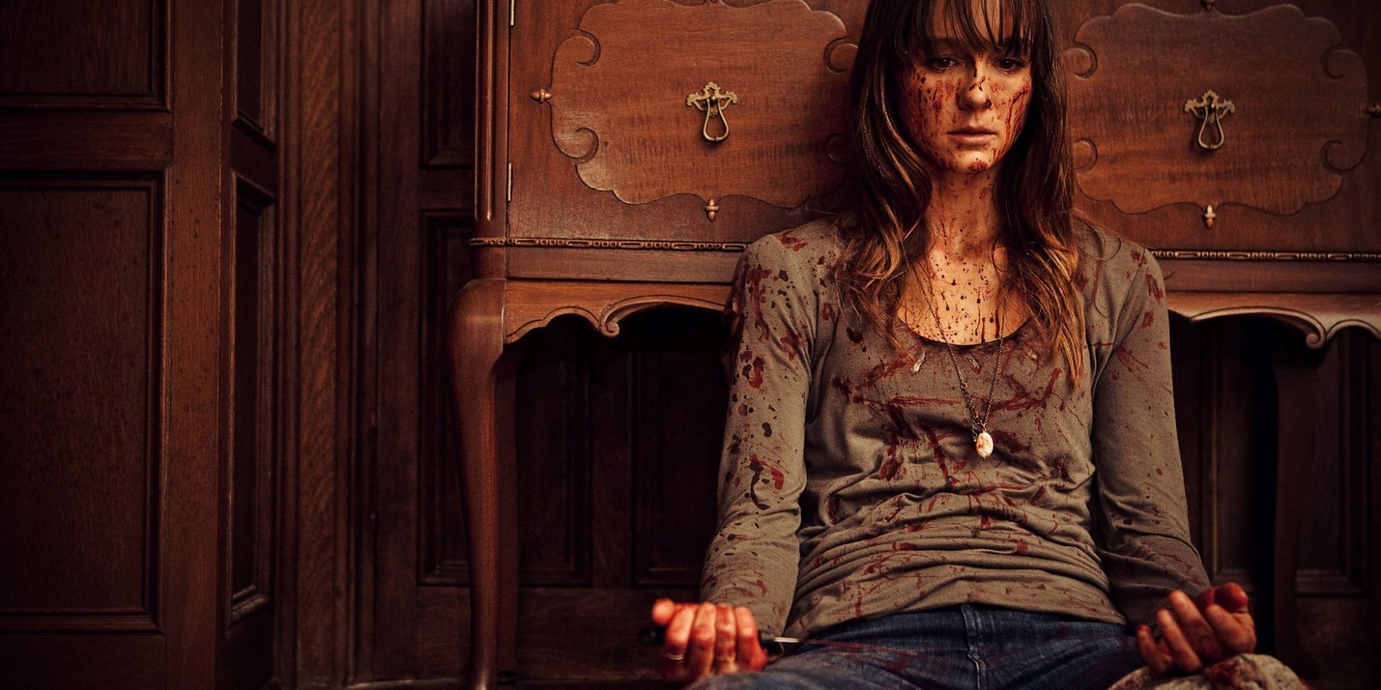 Sharni Vinson dans le rôle d'Erin couverte de sang assise sur le sol dans You're Next