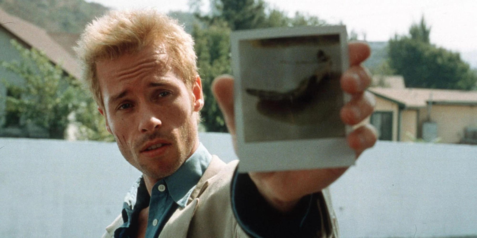 Guy Pearce as Leonard Shelby showing a polaroid to someone off-camera in Memento