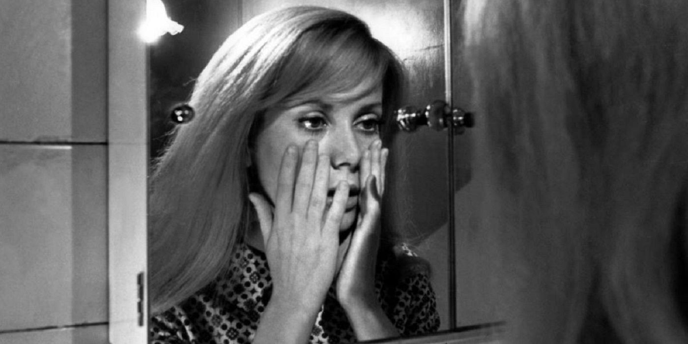 Catherine Deneuve looking at her reflection with her hands on her face in Repulsion