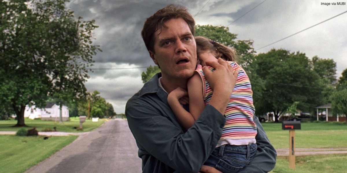 A man carrying a child and running away from a grey cloud in the film Take Shelter