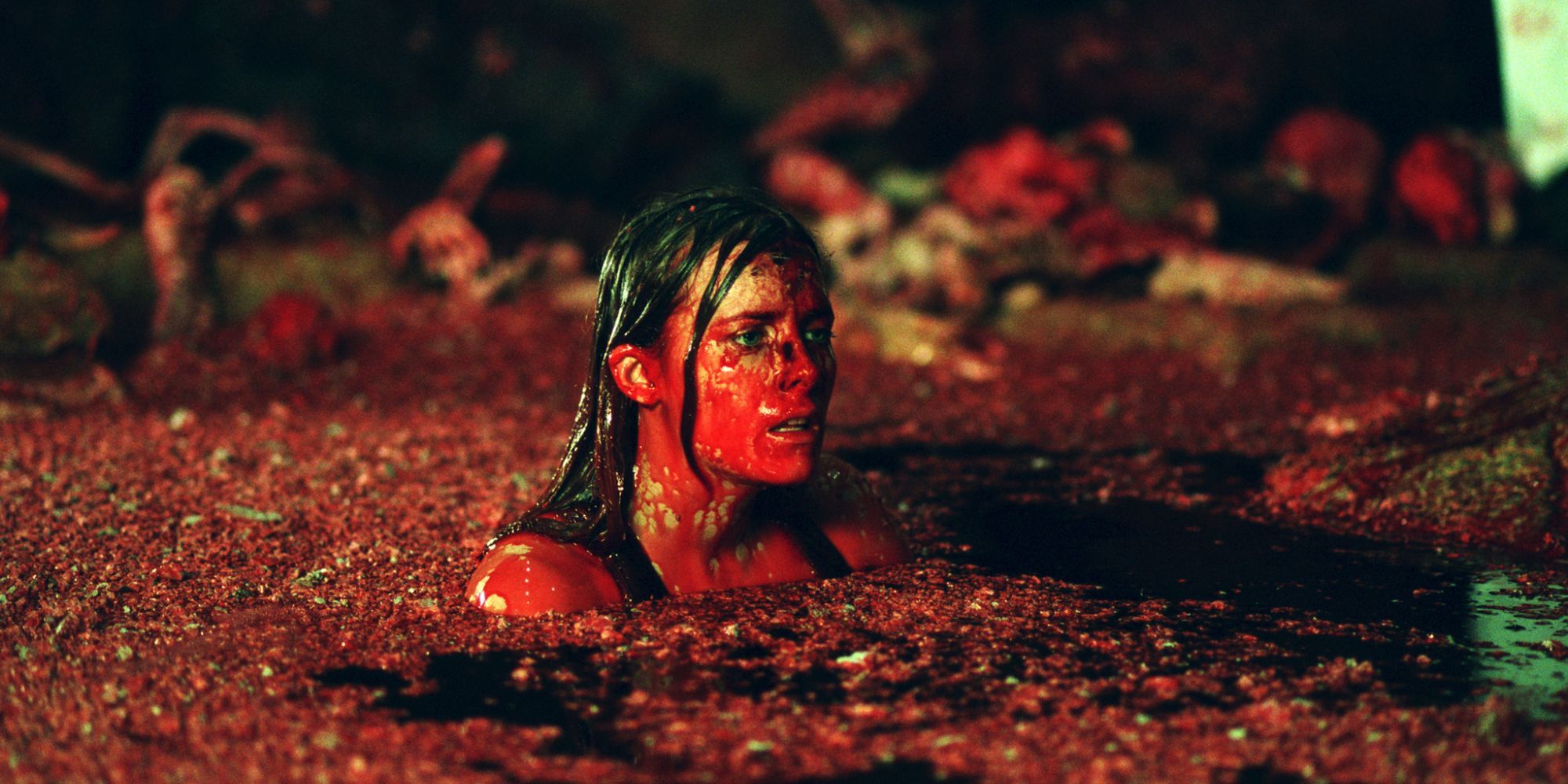 Uma mulher banhada em sangue em uma poça de cadáveres em The Descent (2005)