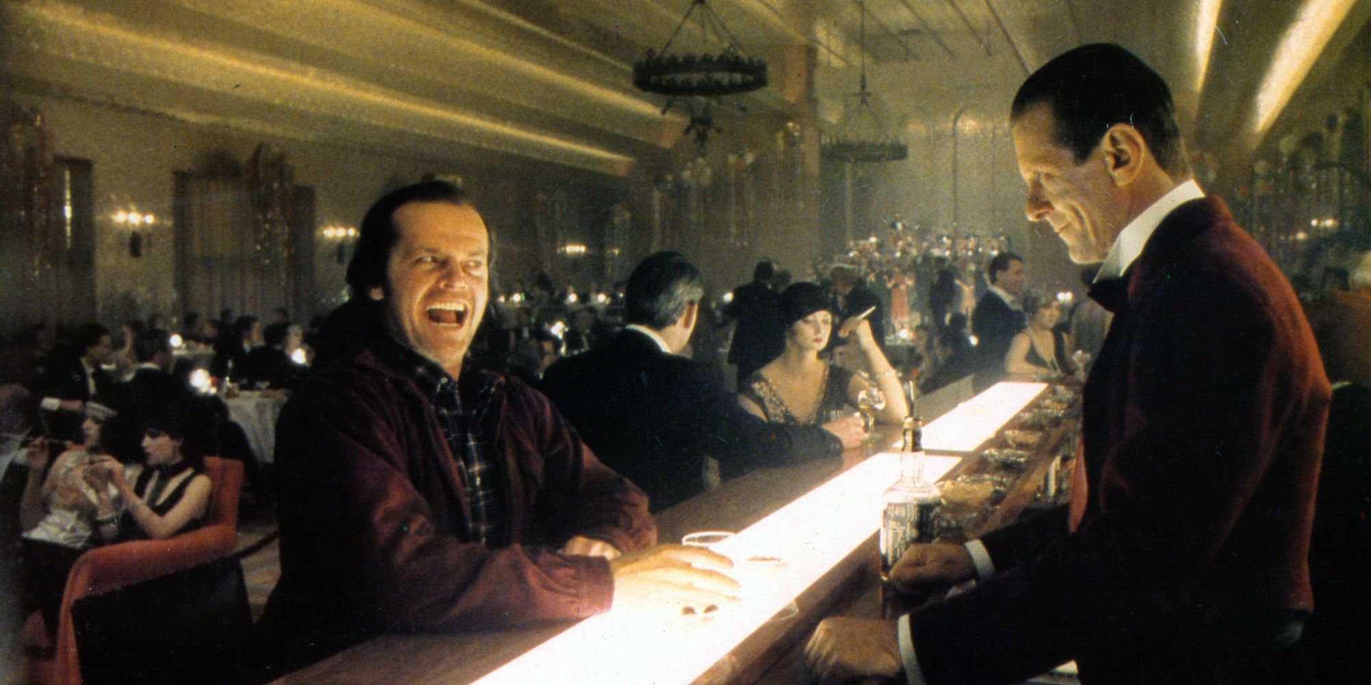 Jack Nicholson as Jack Torrence, smiling maniacally while seated at the busy bar at The Overlook Hotel