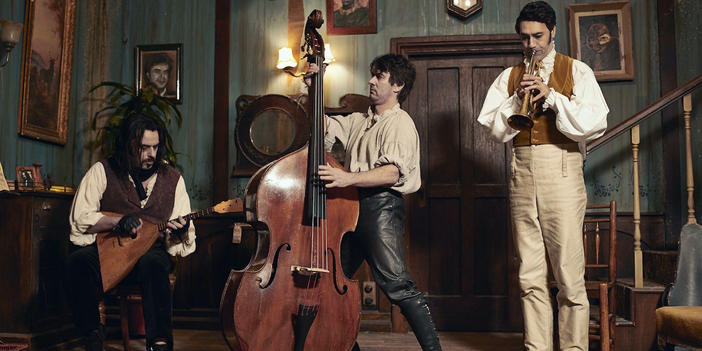 Taika Waititi, Jonathan Brugh, and Jermaine Clement playing musical instruments in What We Do in the Shadows