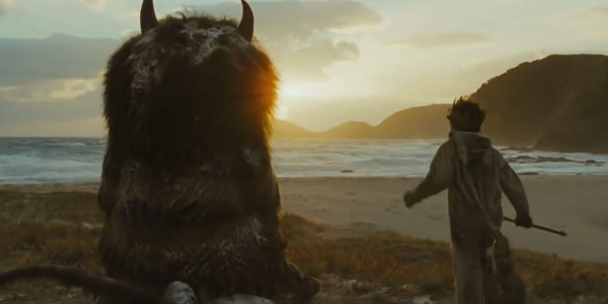 A young boy next to a monster looking at the sunset in Where the Wild Things Are