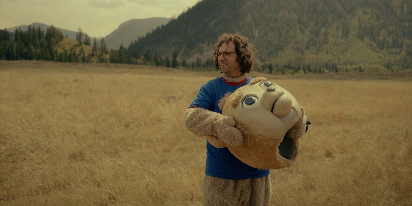 James Pope wearing a bear costume standing in an open field in Brigsby Bear