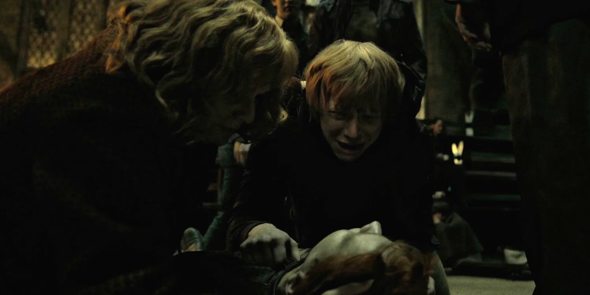 Fred Weasley lies dead on the ground as Ron and Molly Weasley cry over him