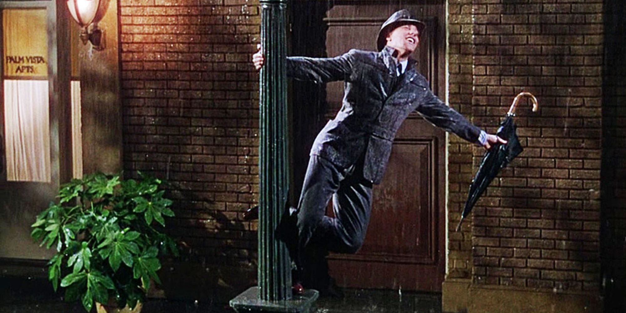 Gene Kelly dances on a lamppost as he sings in the rain