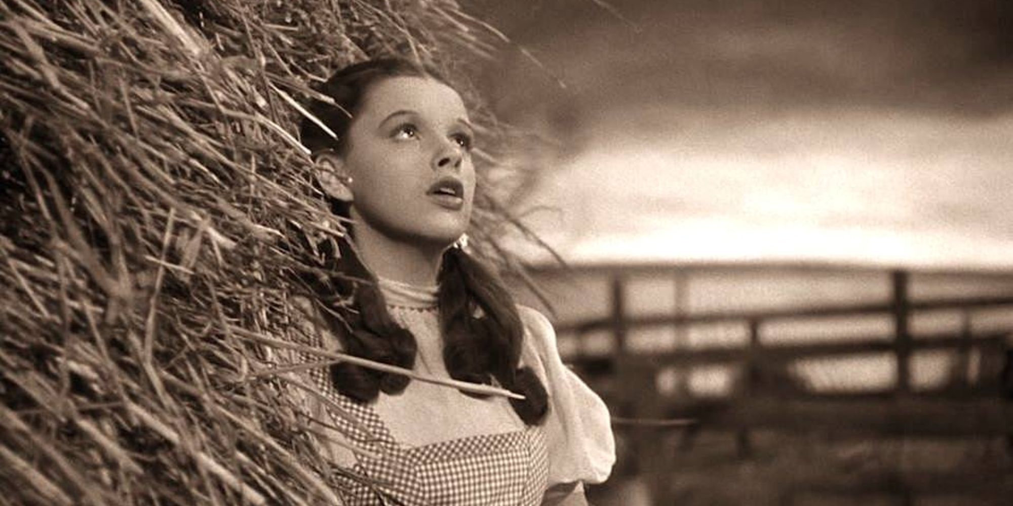 Dorothy leans against a haystack as she sings 'Somewhere Over the Rainbow'