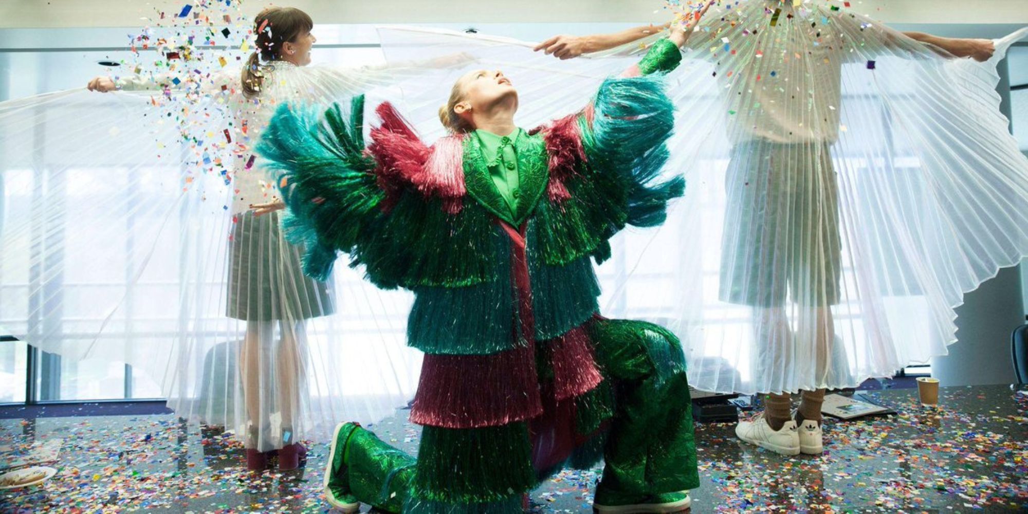 Kit wearing a shiny streamer suit throwing confetti in the air