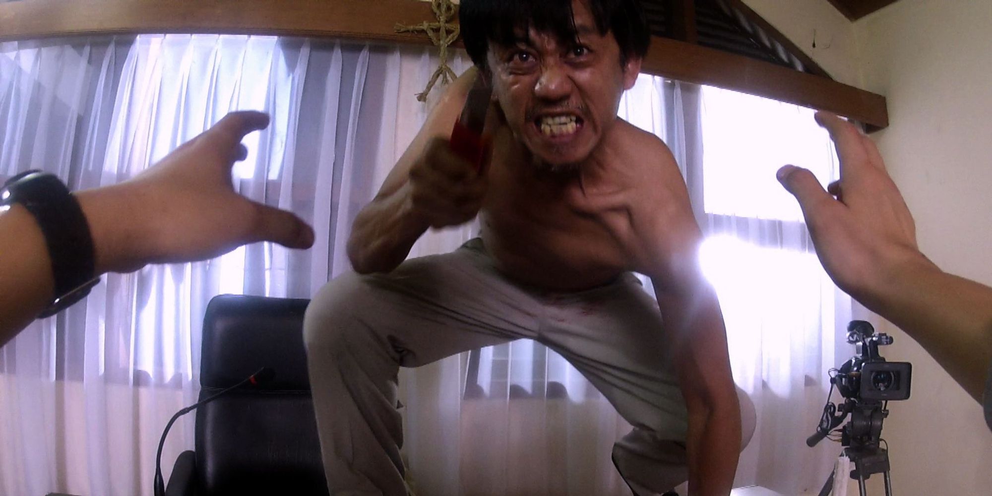 A man aggressively lunges at the camera with a weapon in VHS 2.
