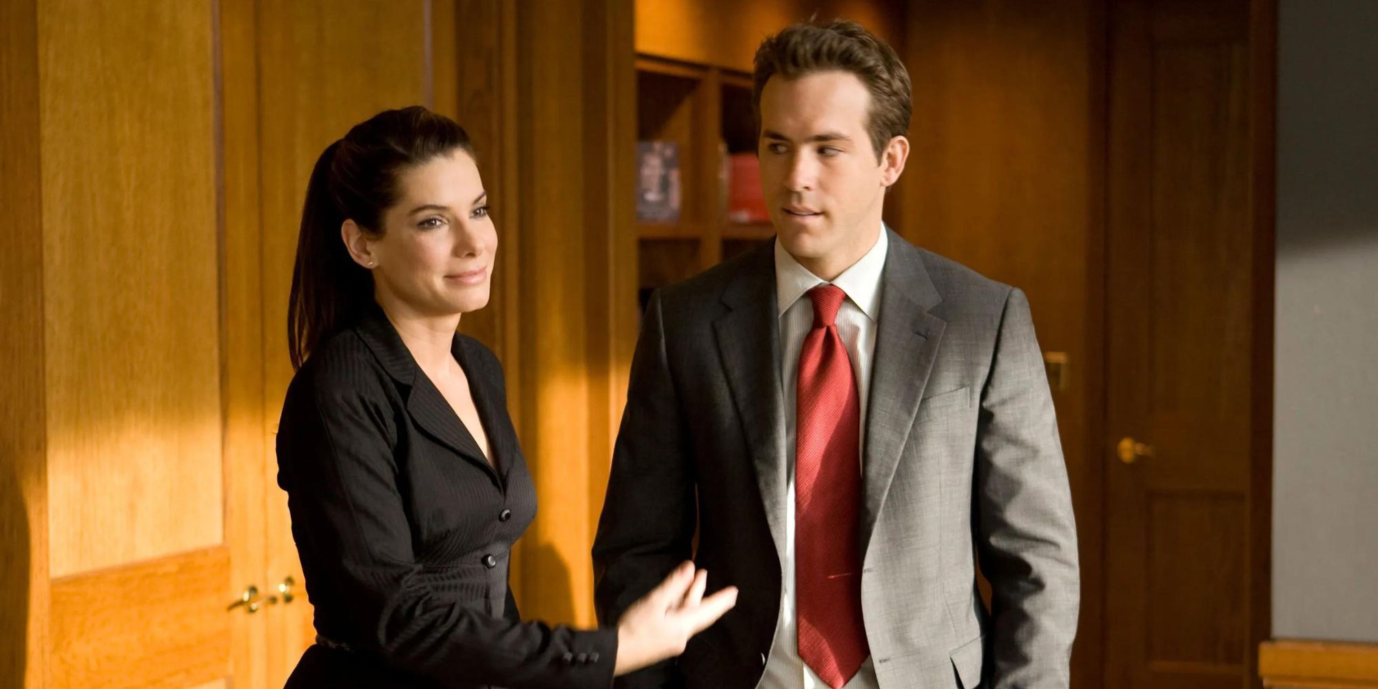 Margaret and Andrew from The Proposal standing together in an office