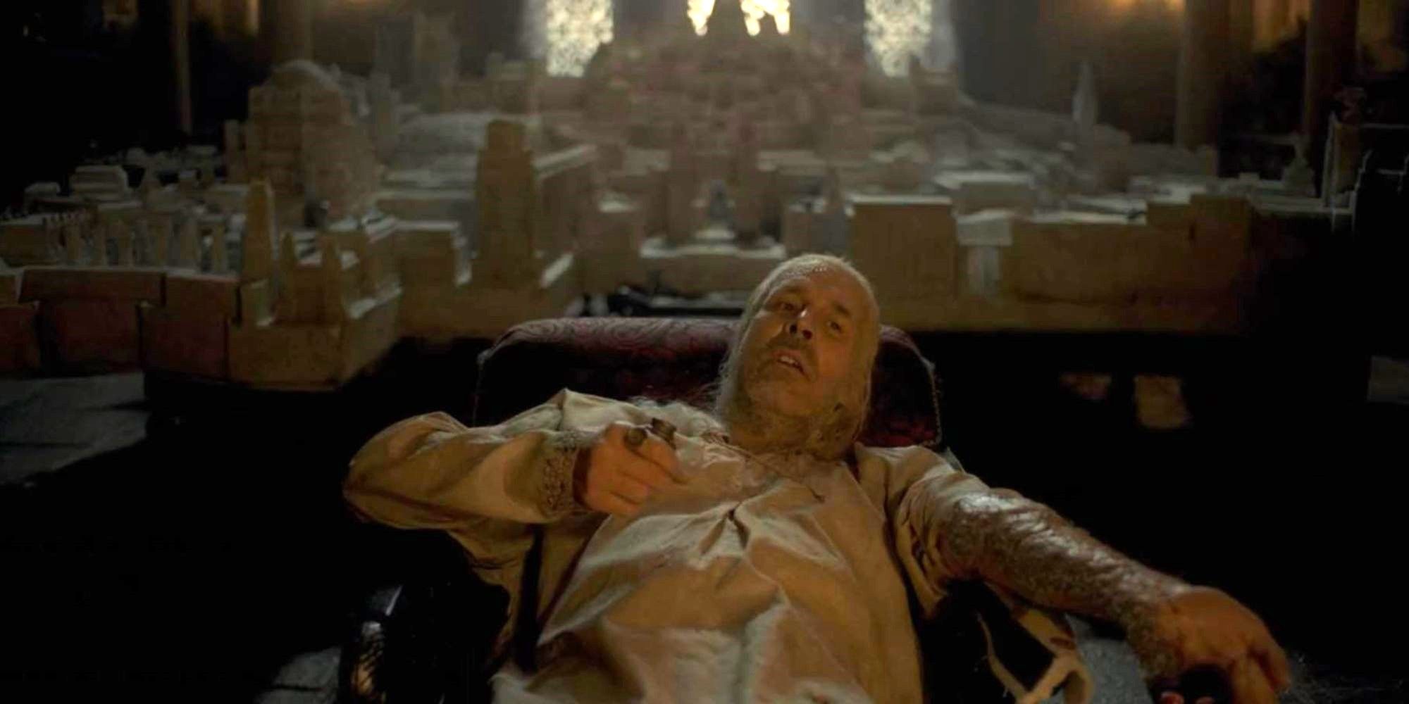 a man sits exhaustingly with his city model behind him