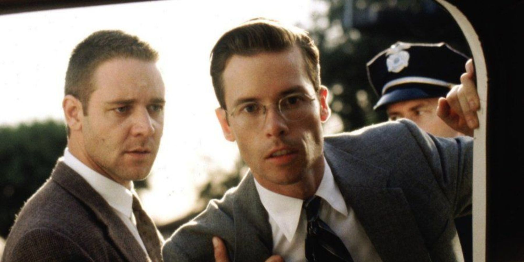 Russell Crowe standing next to Guy Pearce who is looking into a car in L.A. Confidential 