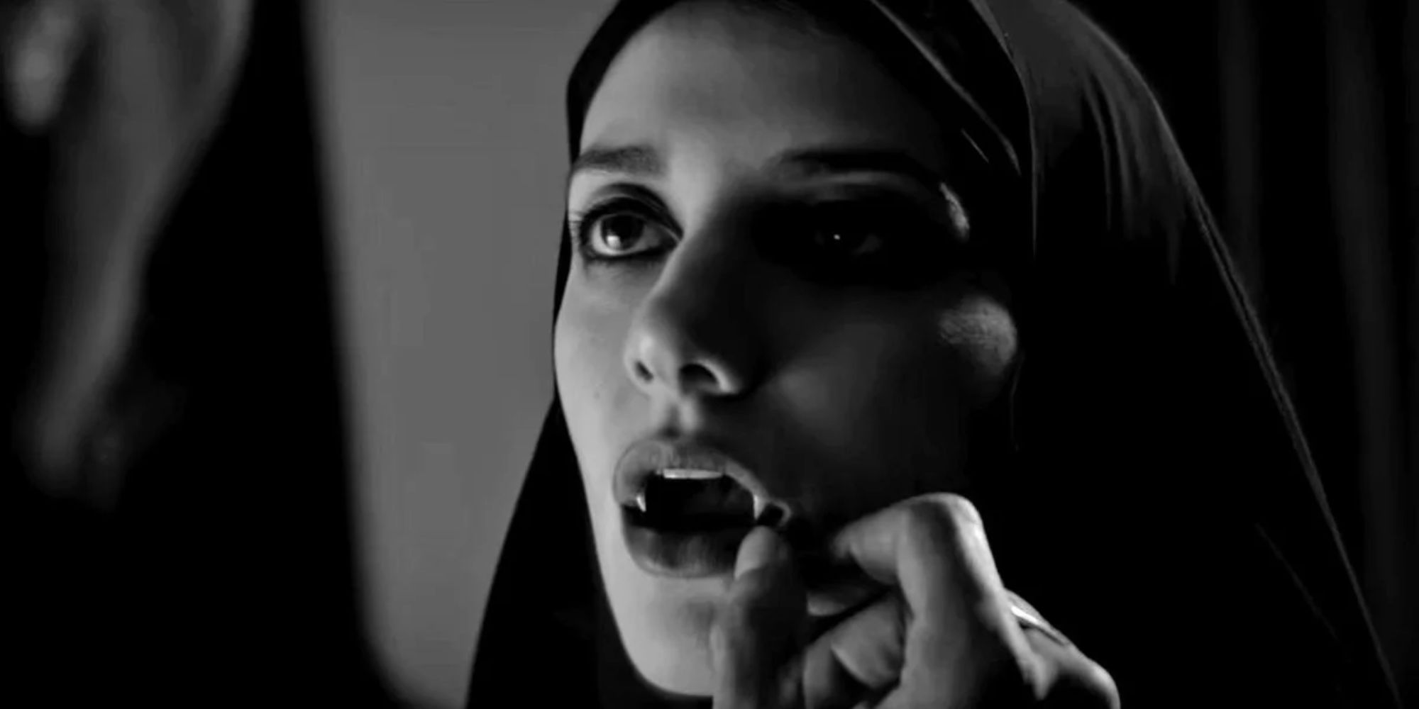 Sheila Vand as The Girl, a young woman with fangs wearing a chador in A Girl Walks Home Alone at Night