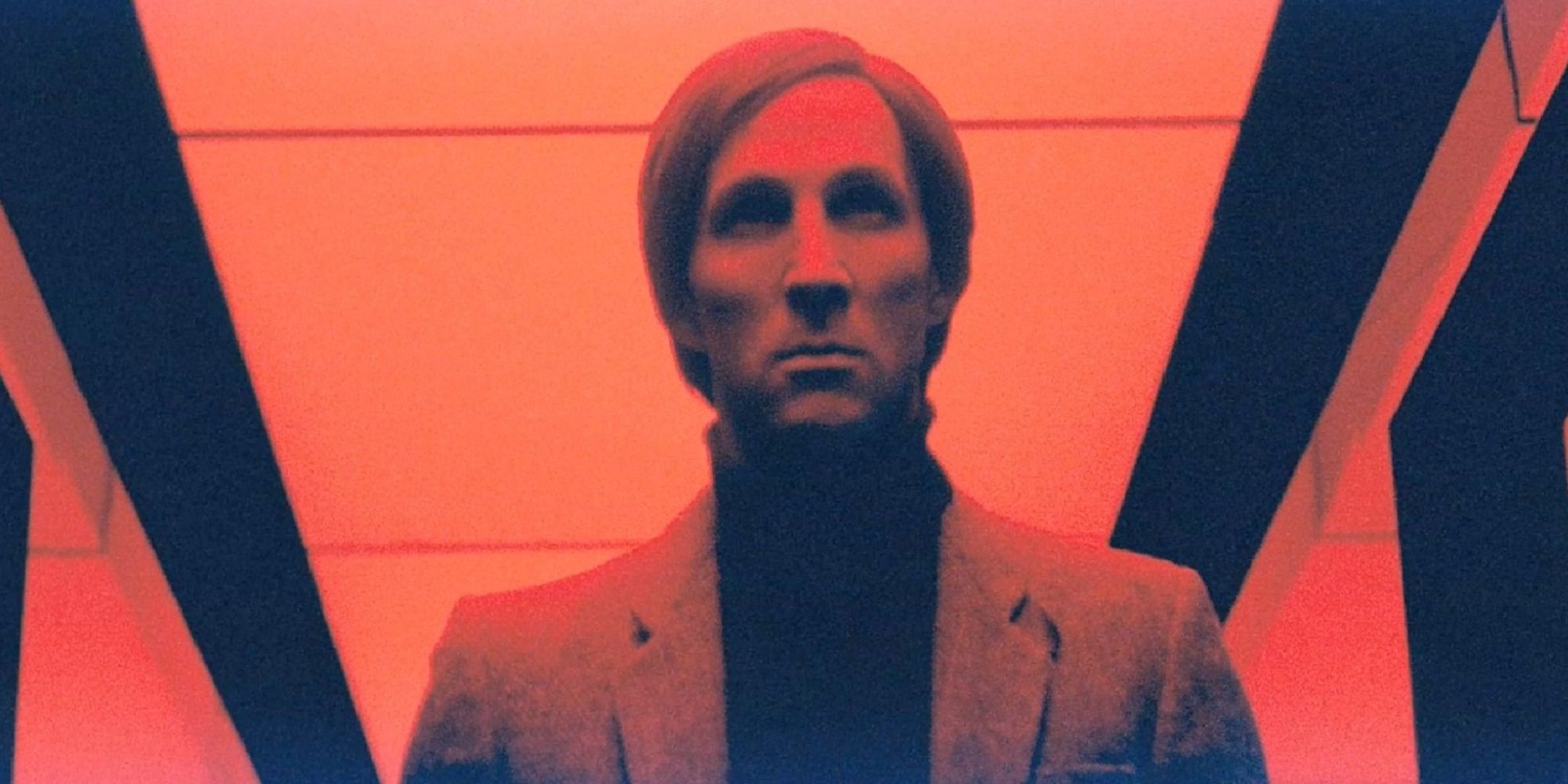 Barry Nile walking down a red-lit hallway in 'Beyond the Black Rainbow.'
