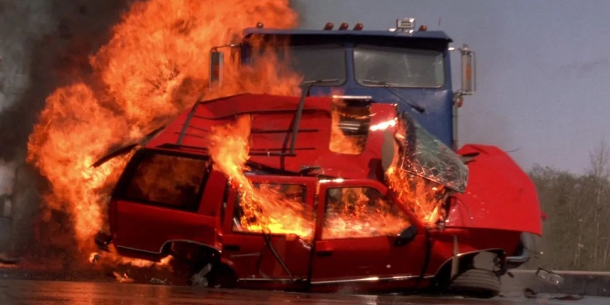 A flaming car hit by a truck