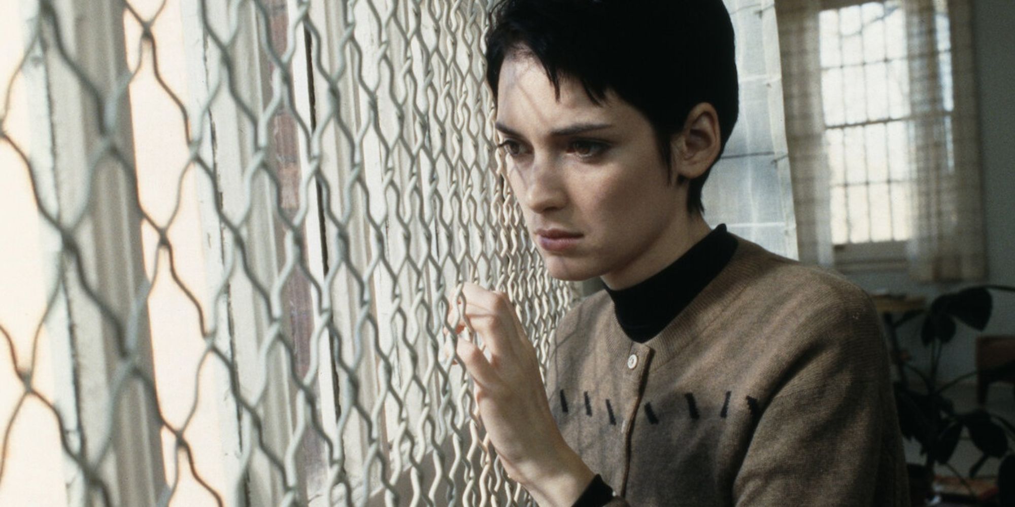 Winona Ryder staring through a wire fence