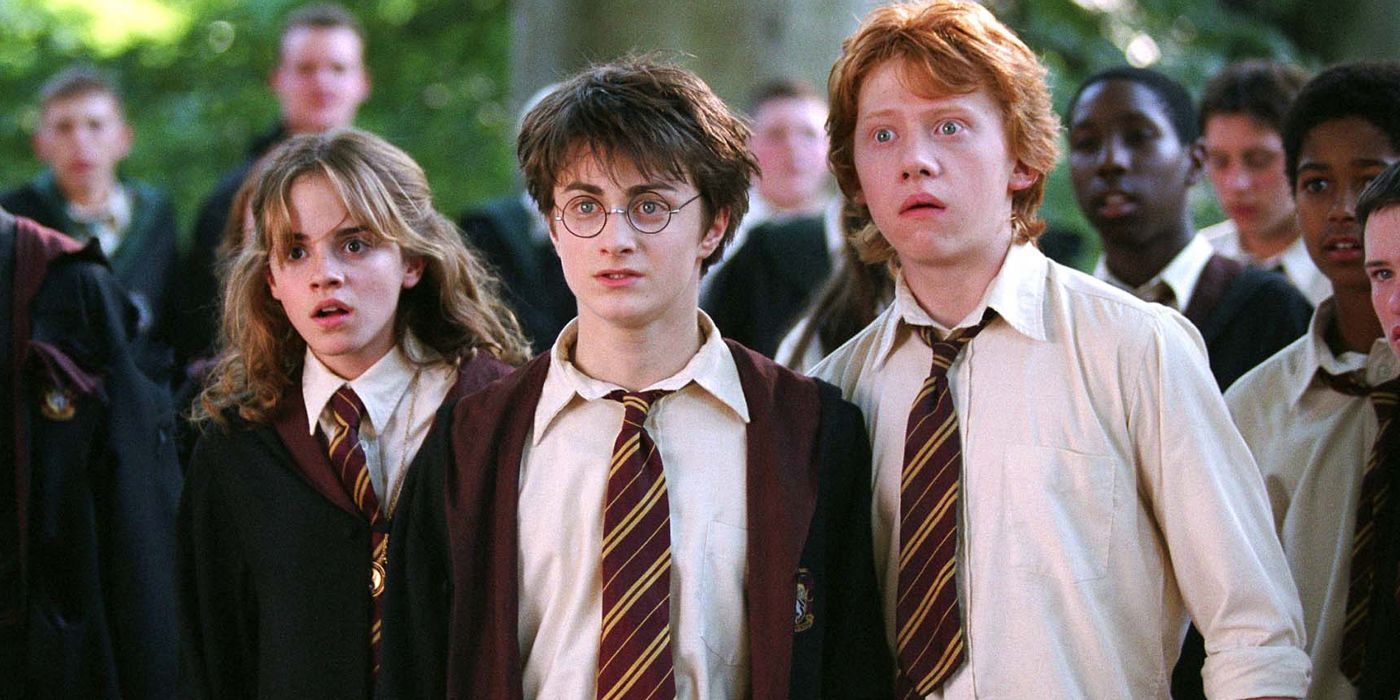 Harry, Hermione, and Ron stand shocked in a crowd of students at Hogwarts in Prisoner of Azkaban