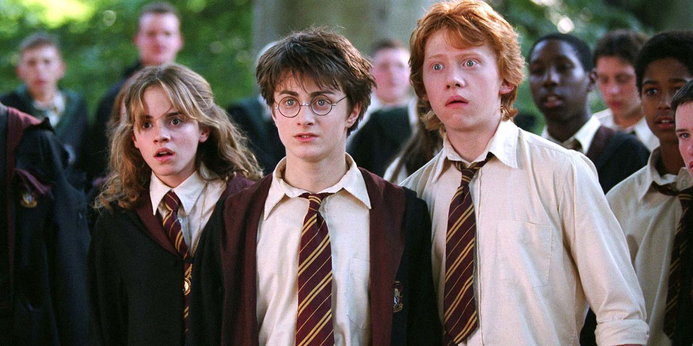 Harry, Hermione, and Ron look shocked in a crowd of students at Hogwarts in Prisoner of Azkaban