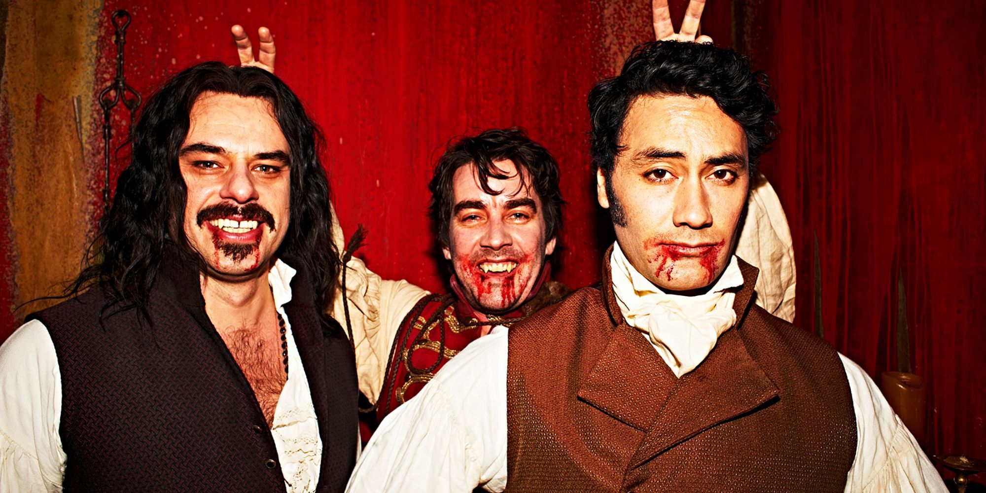 Jemaine Clement as Vladislav, Jonathan Brugh as Deacon and Taika Waititi as Viago, a group of vampires with blood in their mouths posing in What We Do in the Shadows