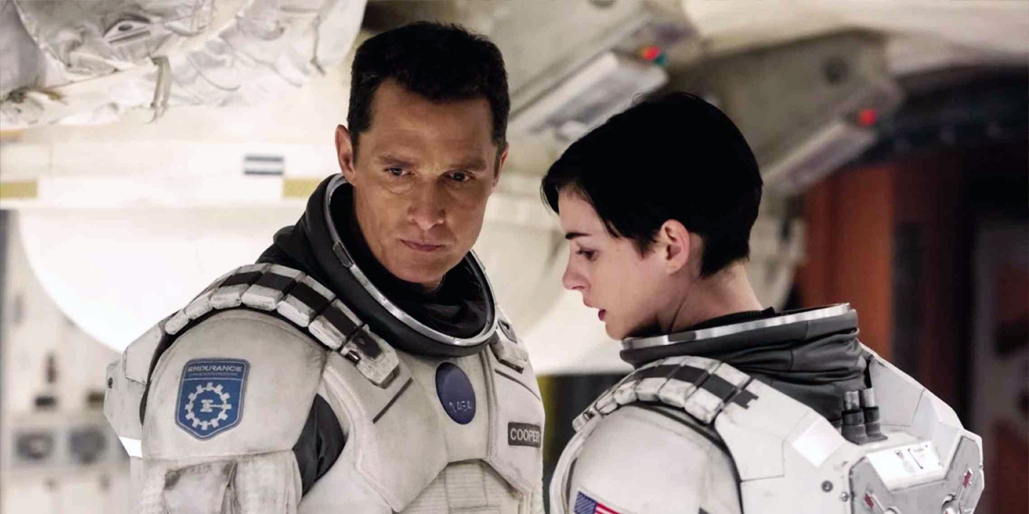 Joseph Cooper (Matthew McConaughey) and Amelia Brand (Anne Hathaway) standing in a spaceship in a spaceship and looking concerned in Interstellar