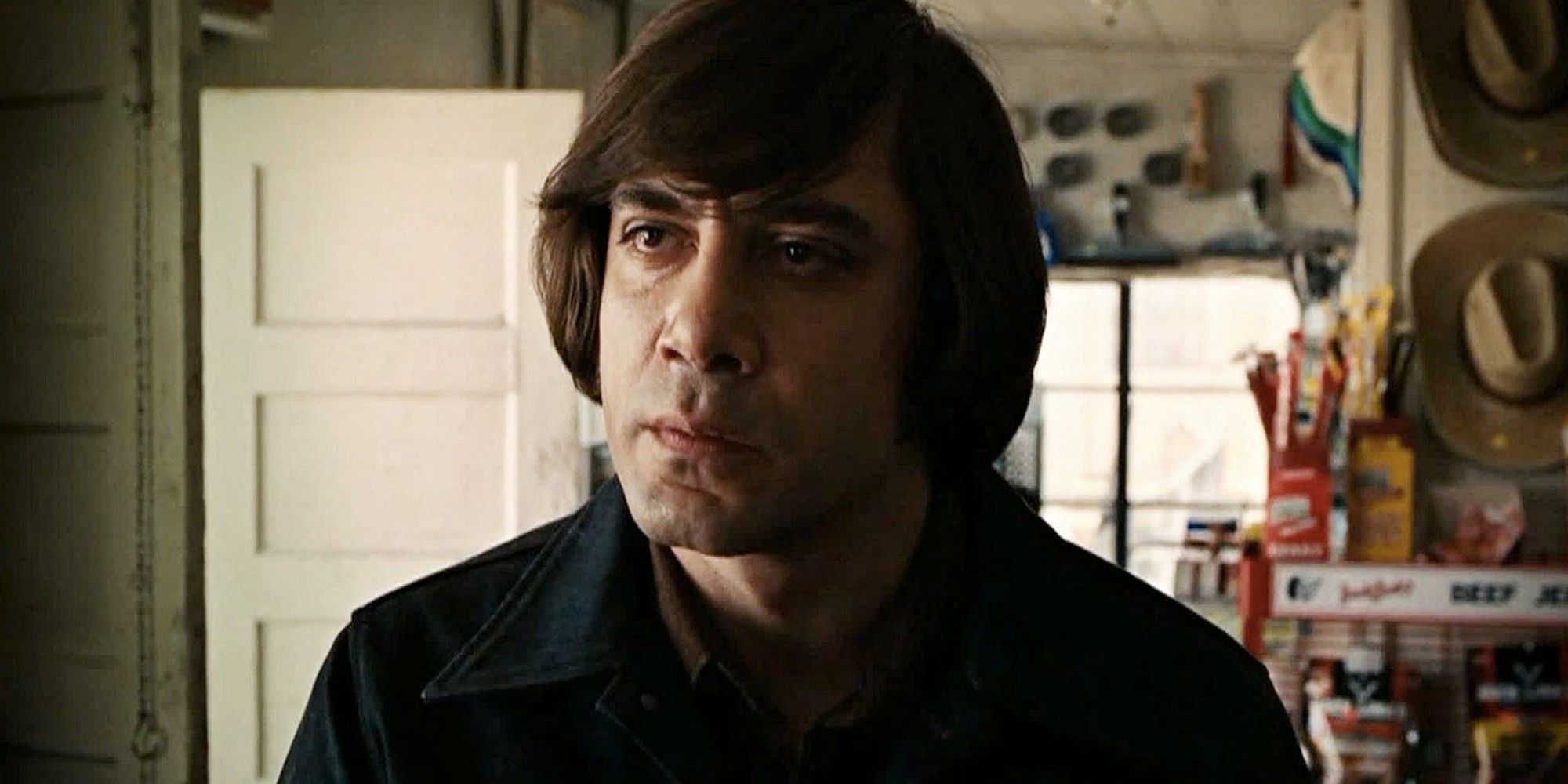 Javier Bardem as Anton Chigurh looking at a man with a scary expression on in No Country for Old Men.