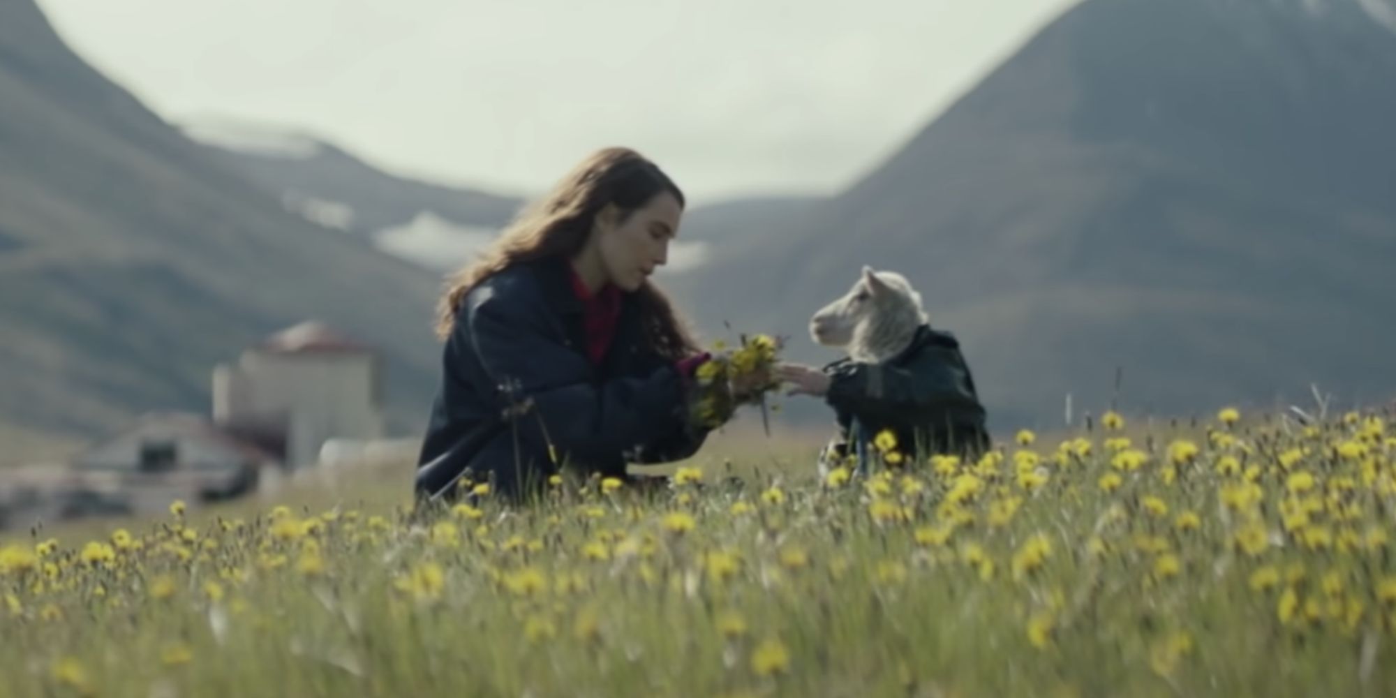 A woman and a small lamb sit among yellow flowers in Lamb.