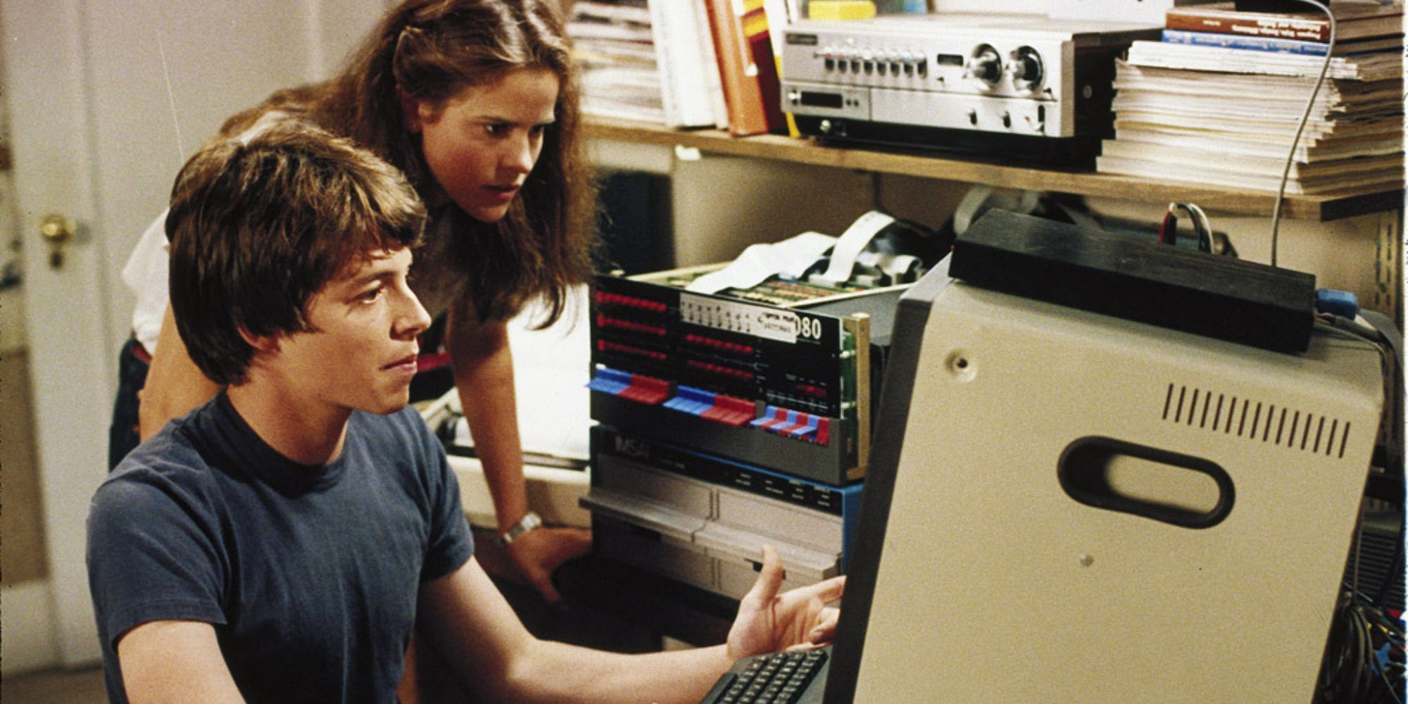 Two teenagers express concern as they look at a game on a computer.