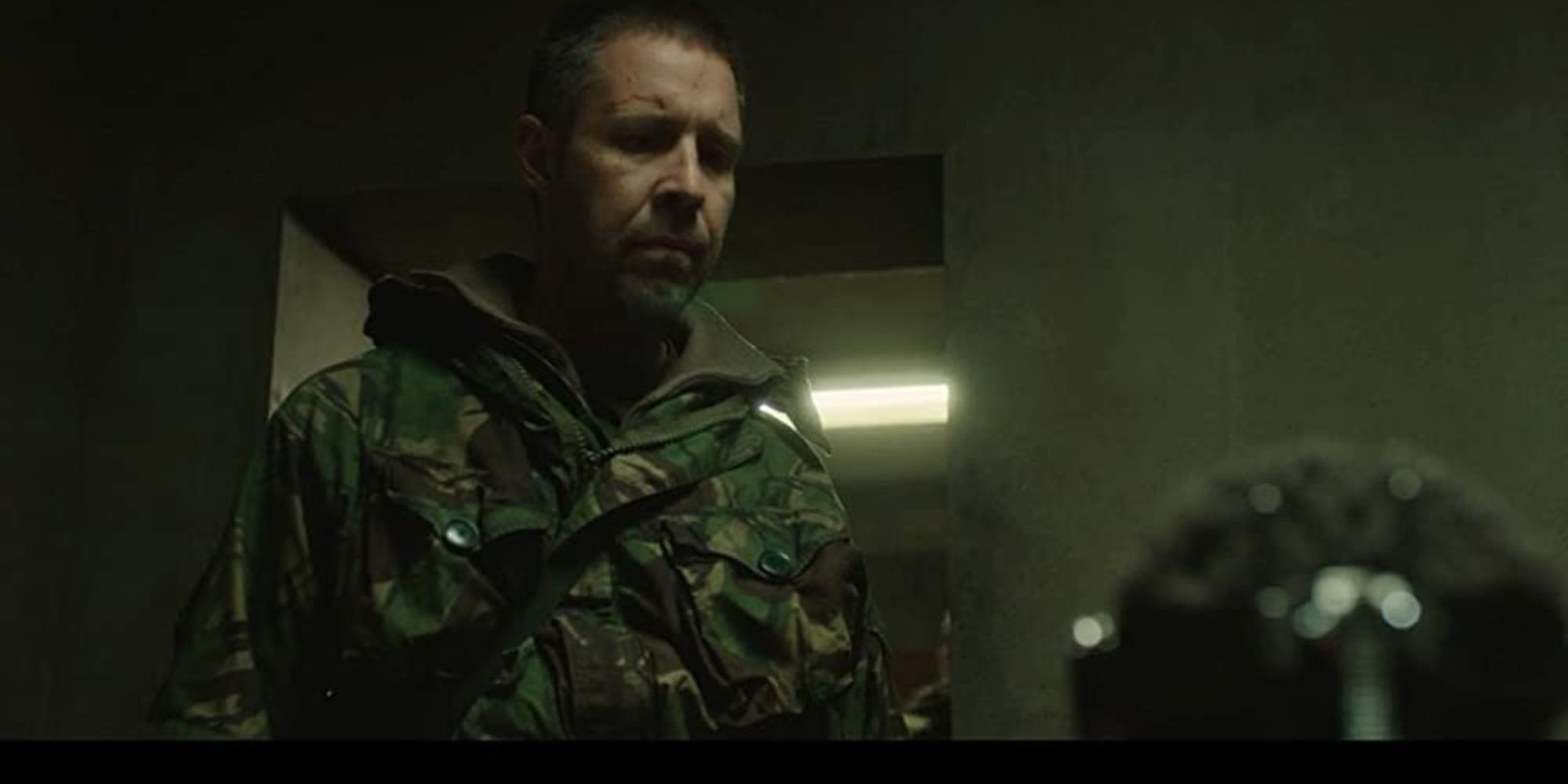 A man in millitary looks upset in a very dark room