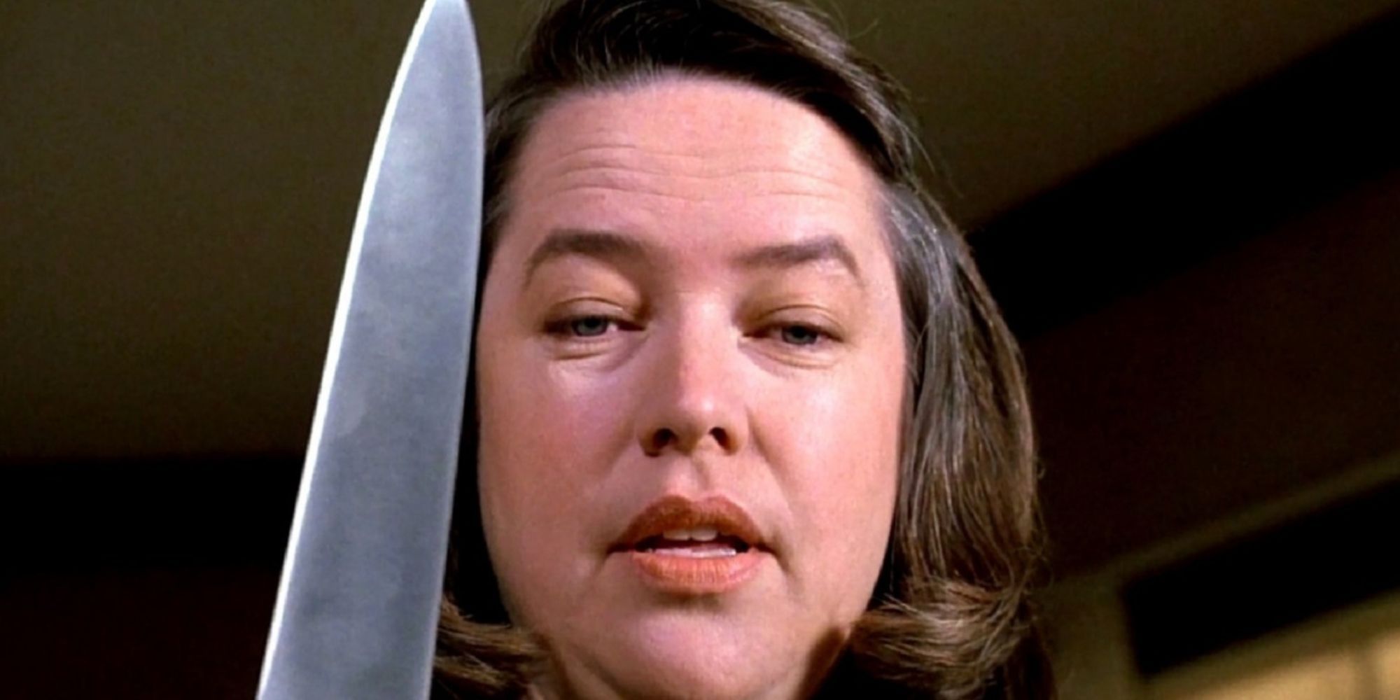 Annie Wilkes tient un couteau et a l'air sérieux dans Misery.