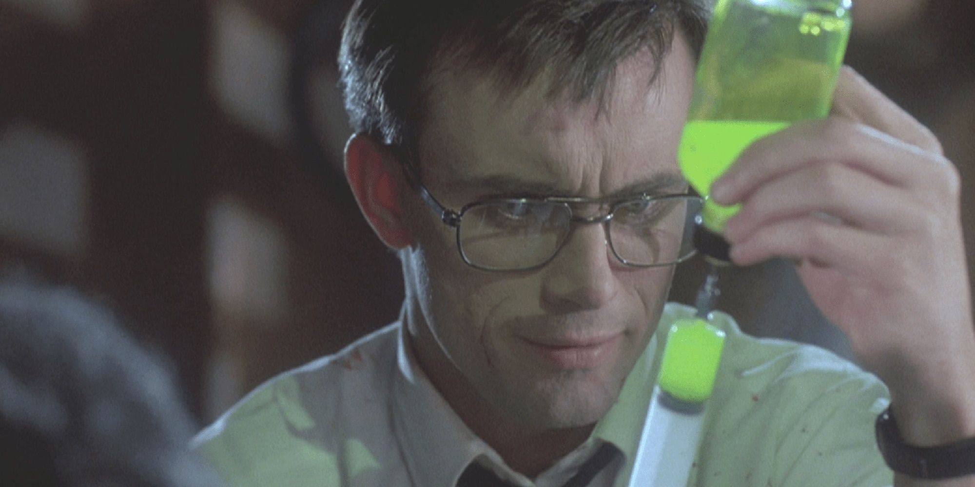 Herbert West filling a syringe with a green liquid in 'Re-Animator.'