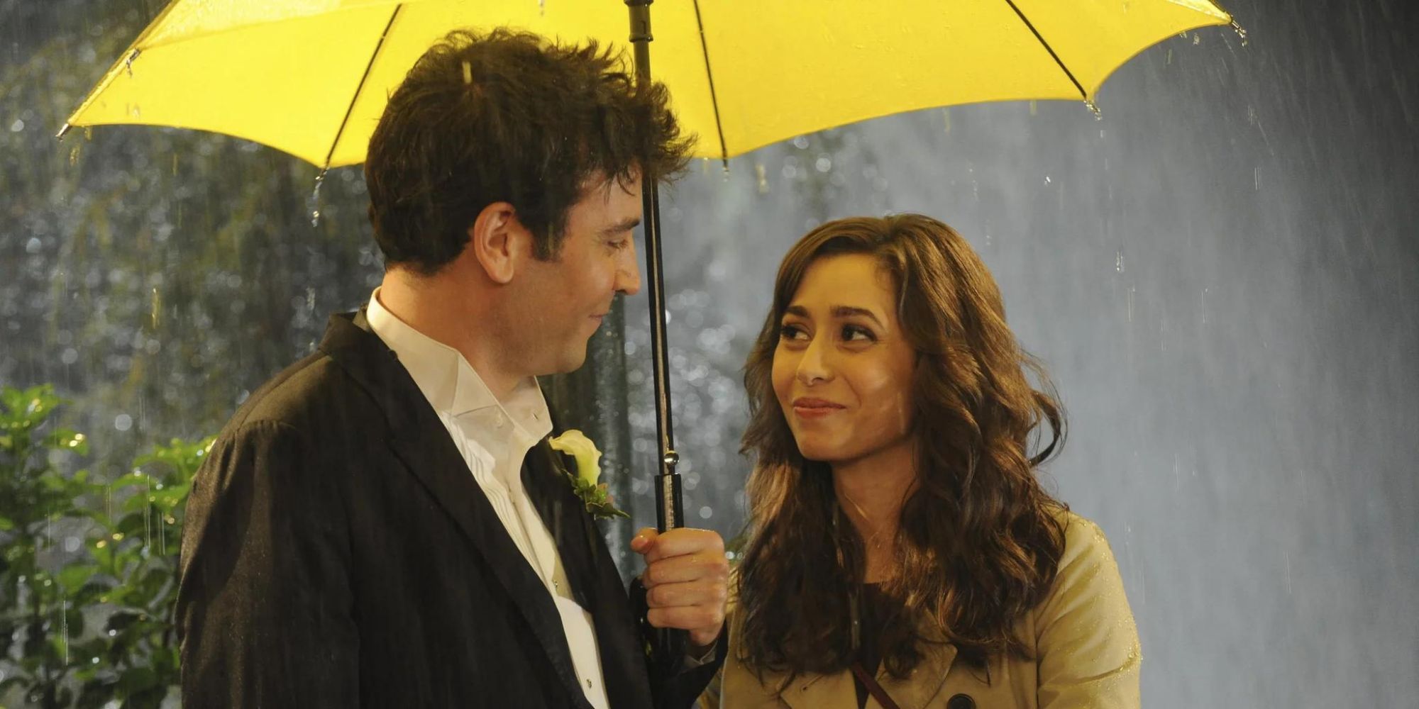 Ted and Tracy smile at one another under an umbrella in a downpour of rain in How I Met Your Mother.