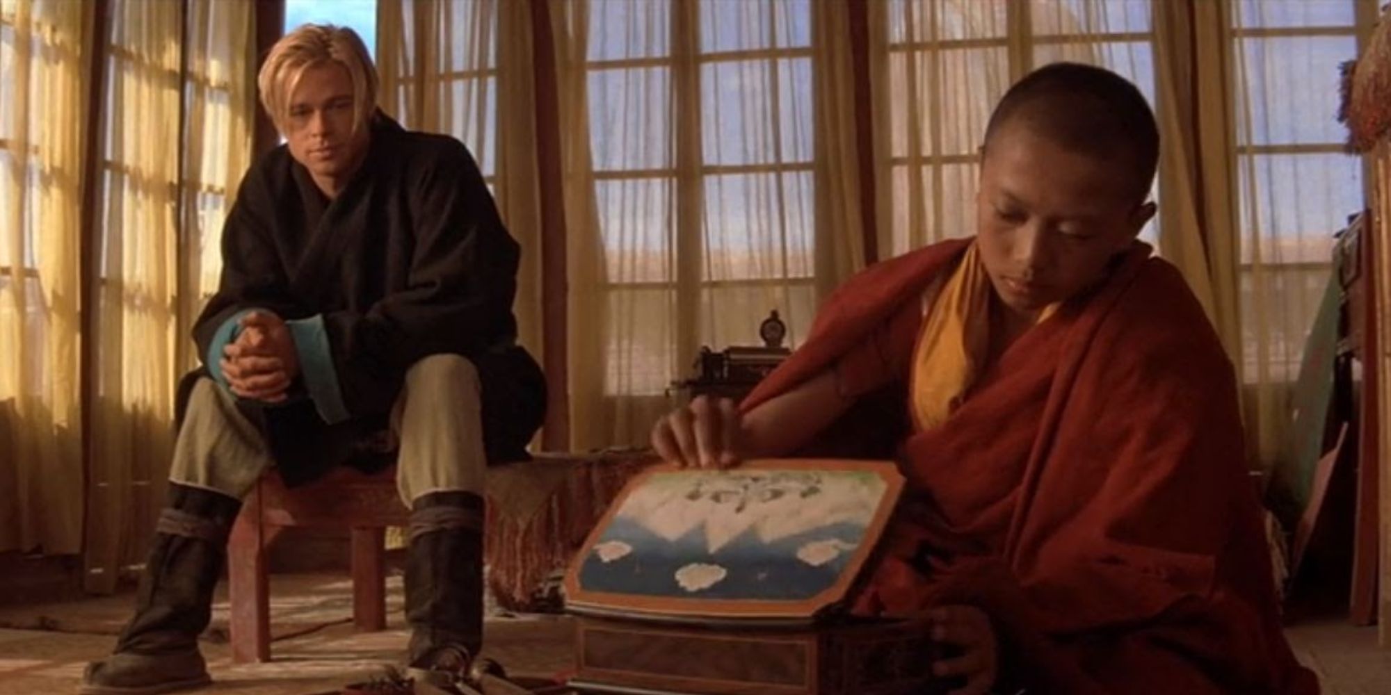 a blonde man watching a monk opening a box