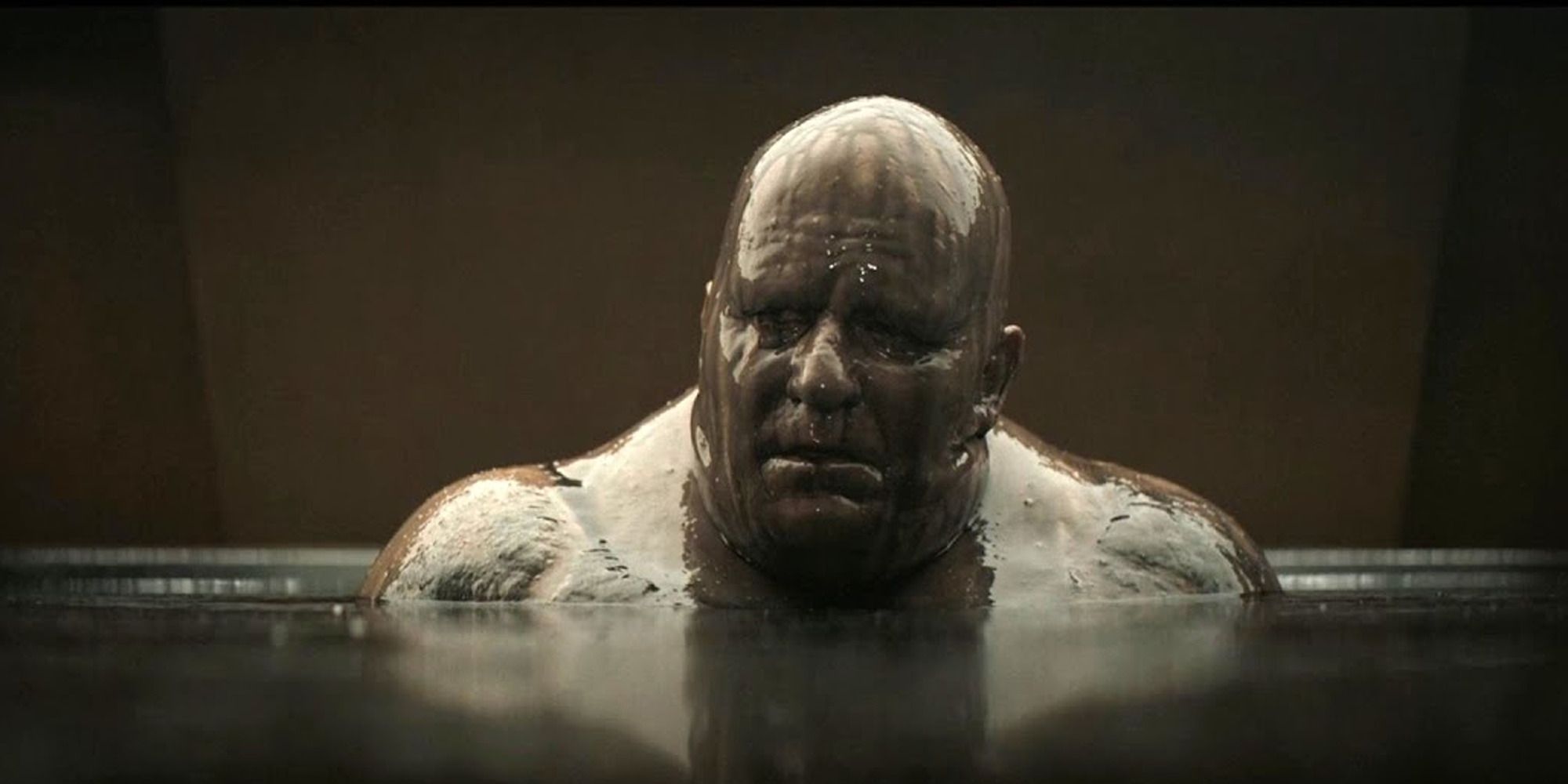 man covered in mud, in a mud bath