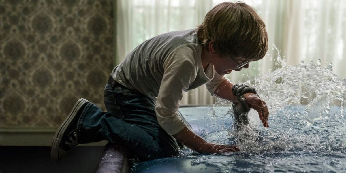 David, played by actor Julian Hilliard, is grabbed by a hand emerging from water in The Conjuring: The Devil Made Me Do It.