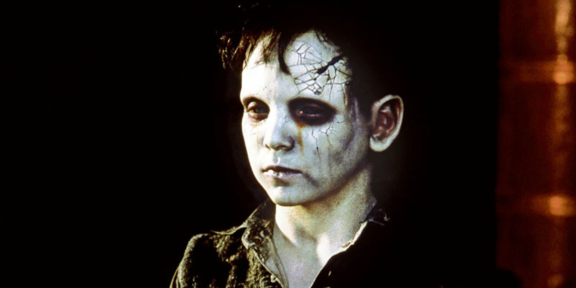 A close-up of a young boy with white faice and horror makeup in The Devil's Backbone 