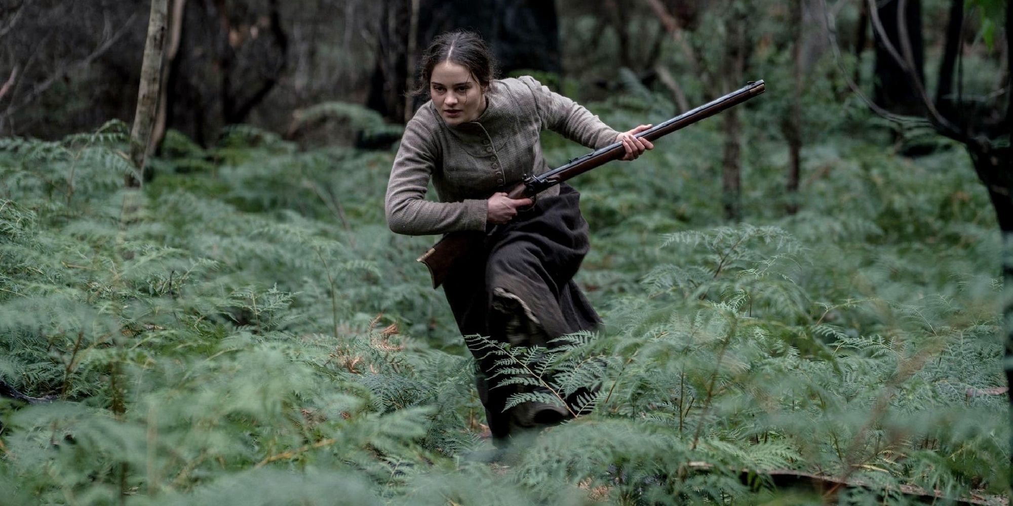 A woman running through a forest with a rifle