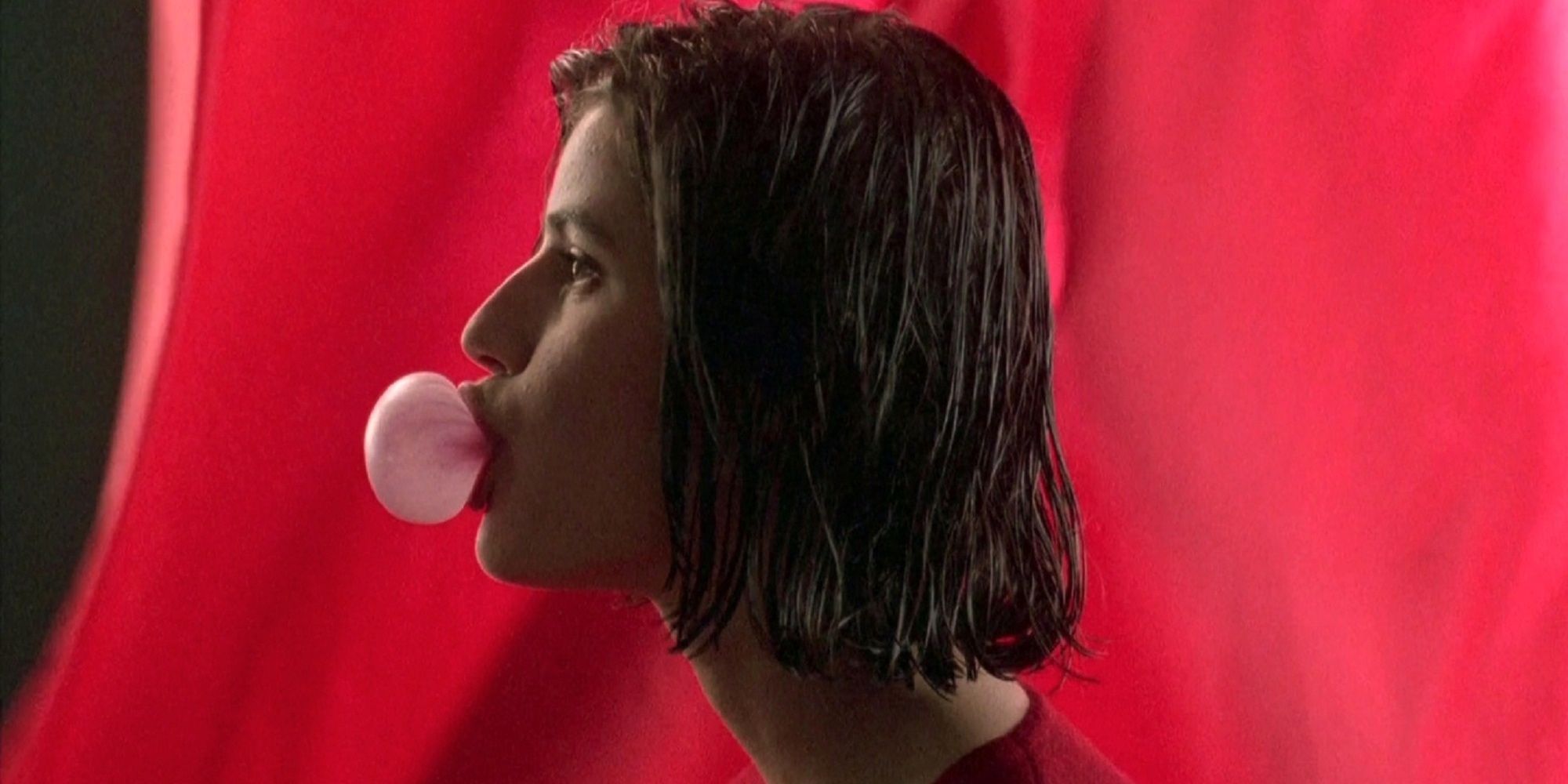 Valentine blowing a bubble with bubblegum in 'Three Colours Red.'