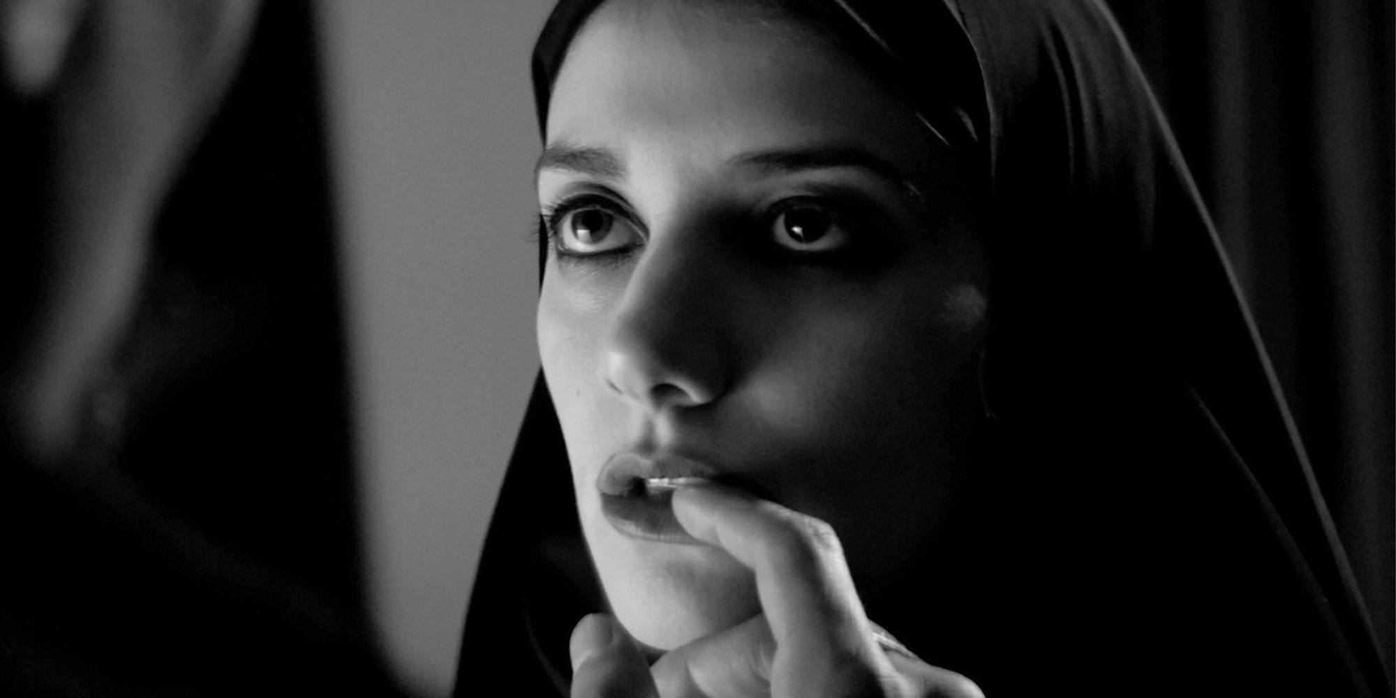 A hand in the mouth of a female vampire in black and white