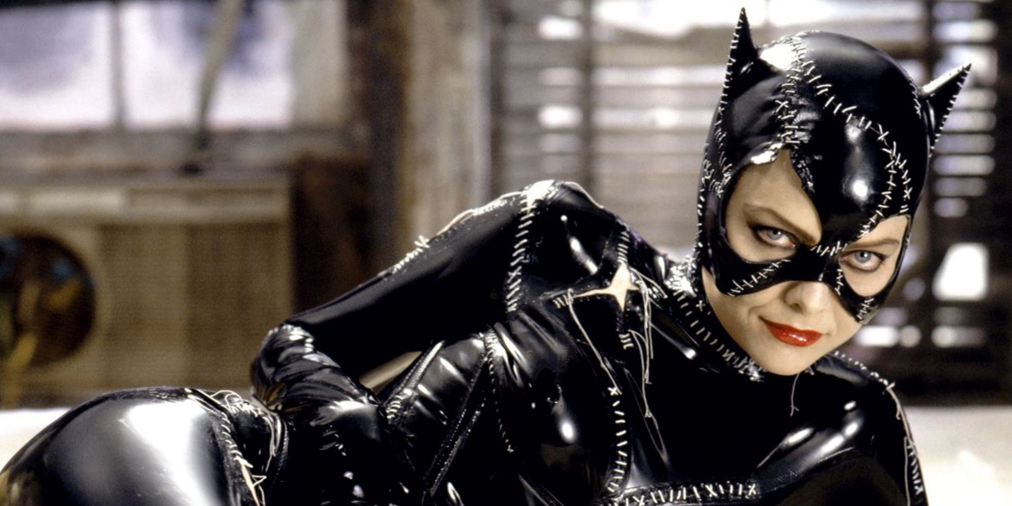 Michelle Pfeiffer as Catwoman reclining in her leather outfit with cat ears in Batman Returns.