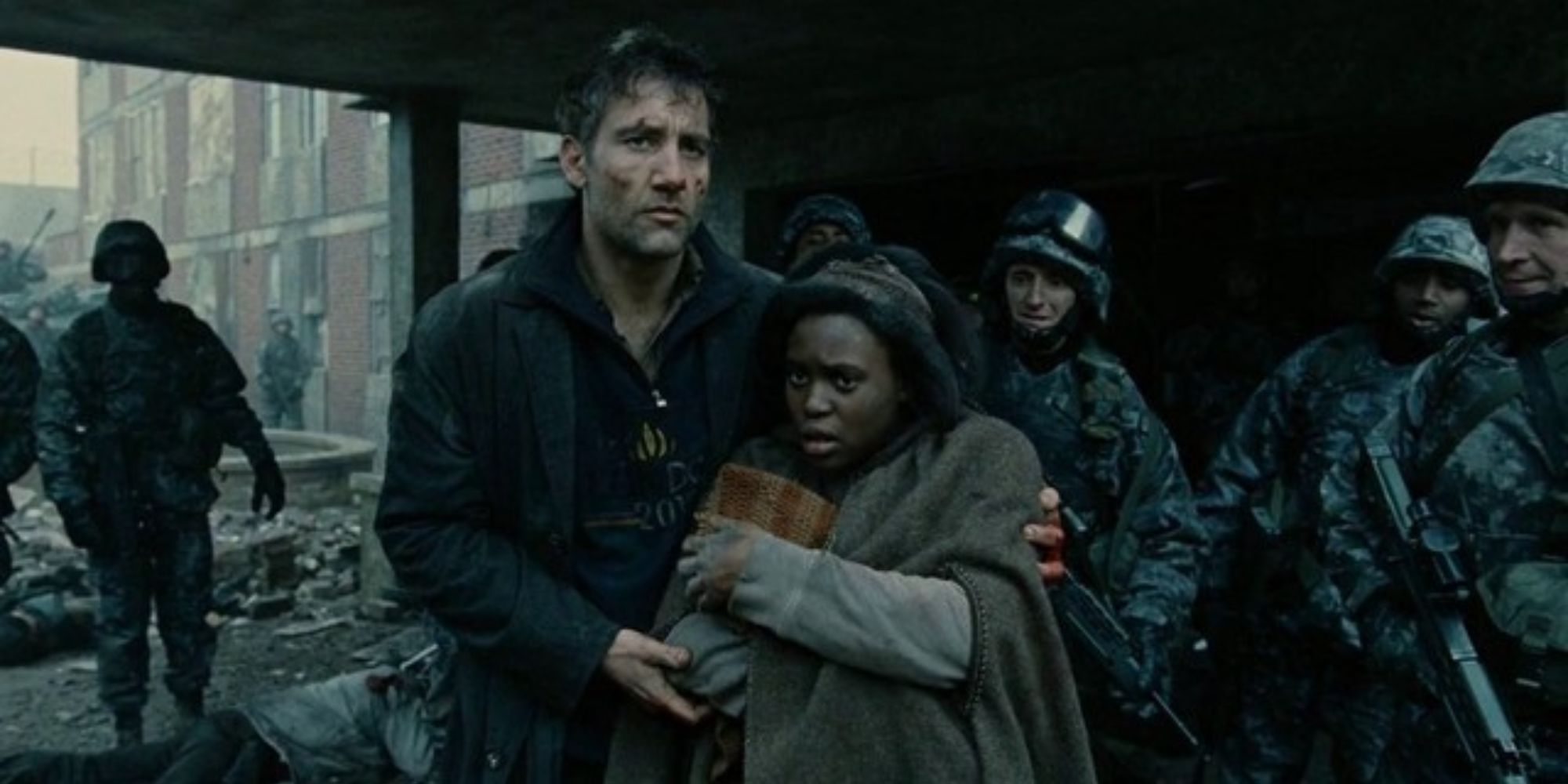 Clive Owen ushers Clare Hope Ashitey away from soldiers as she holds a baby in Children of Men.
