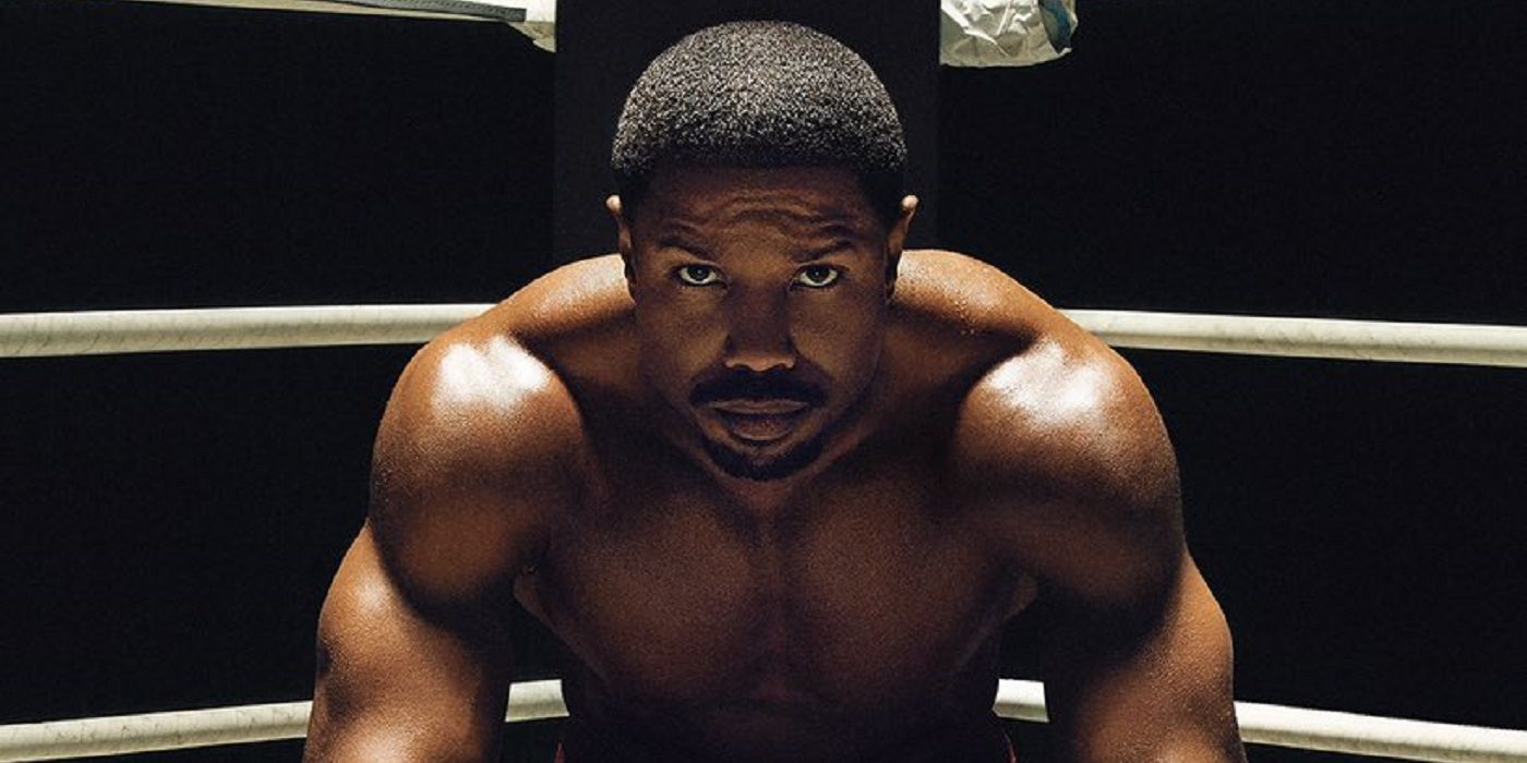 Michael B. Jordan, who plays Adonis Creed in Creed 3, sits in the ring and looks up at the camera.