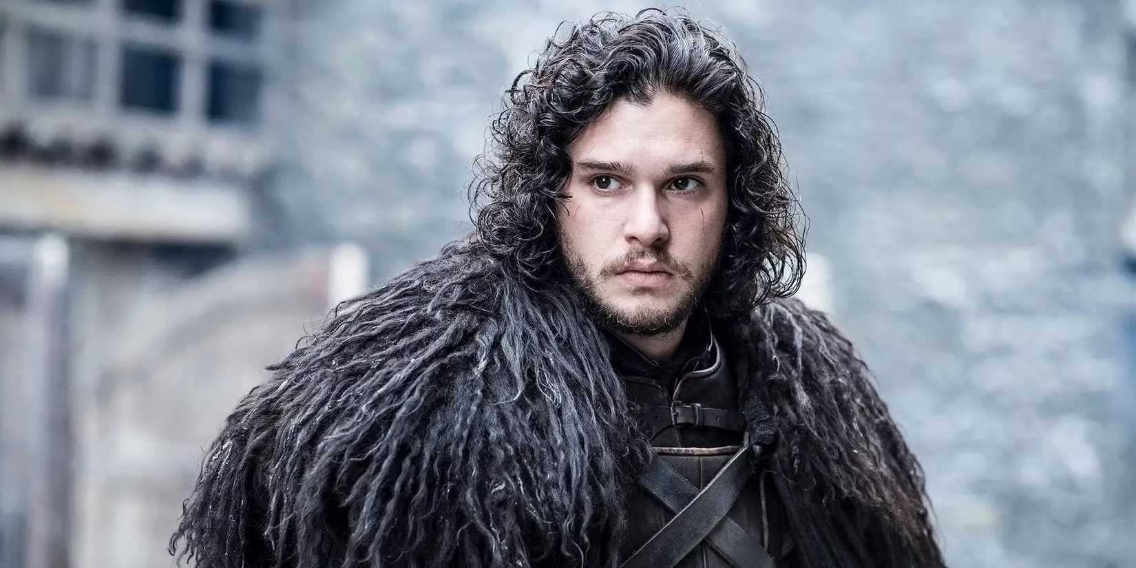 Kit Harrington as Jon Snow in a cloak looking pensive in Game of Thrones.