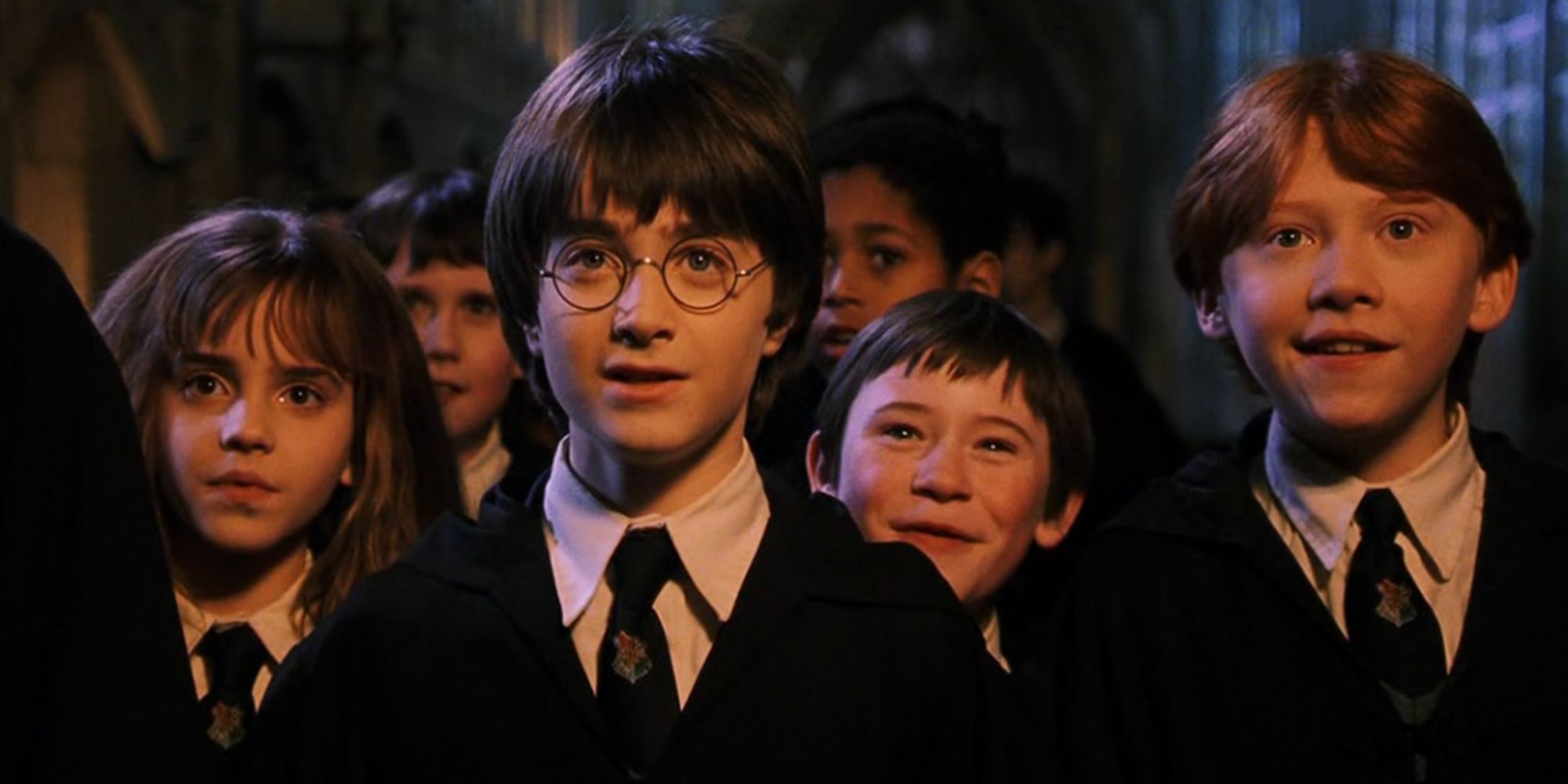 Harry Potter, Ron Weasley, Hermione Granger, Seamus Finnigan, Neville Longbottom et Dean Thomas ensemble dans 'Harry Potter et l'école des sorciers'.