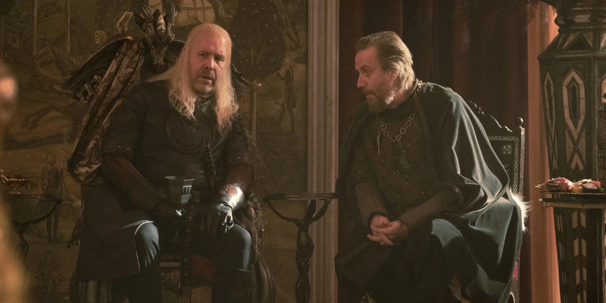 Two men sit side by side talking